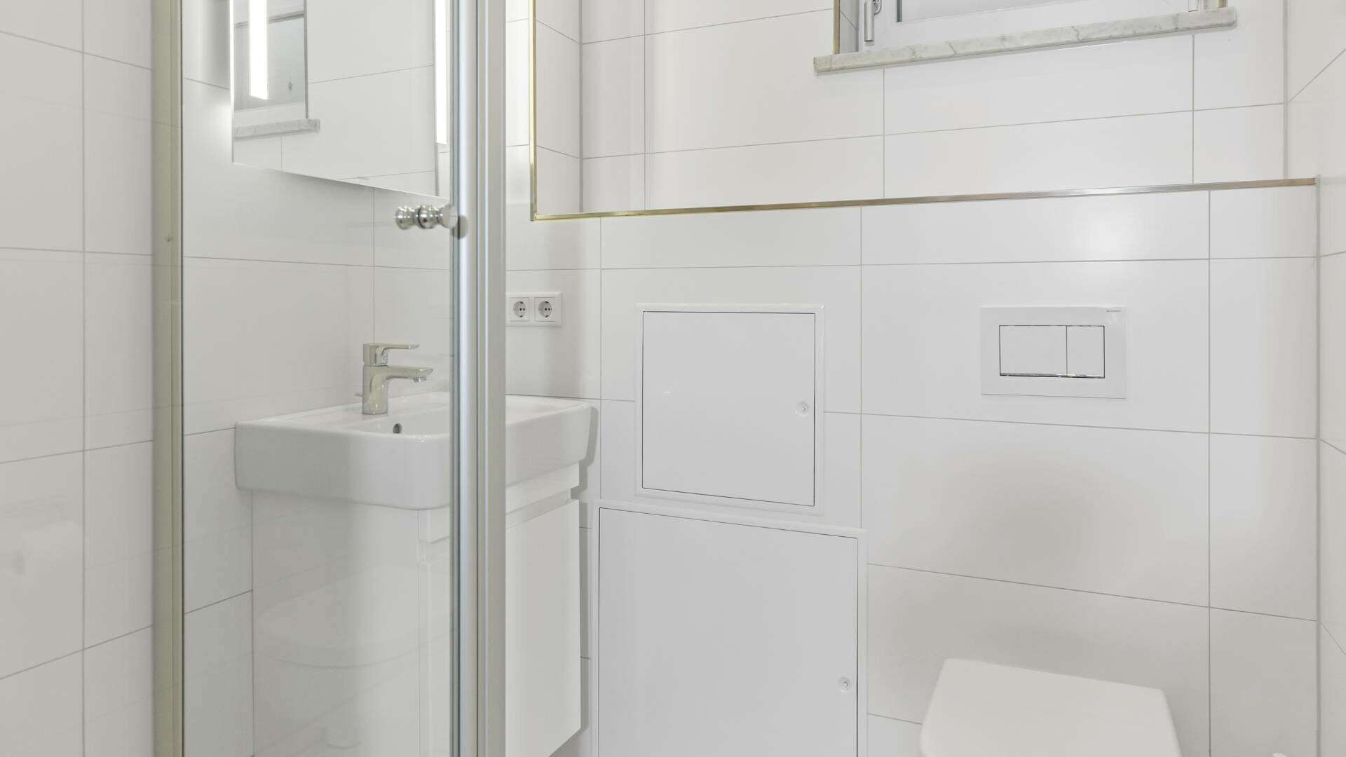 Compact shower room in Lerchenau with a glass shower, washbasin, and white tiles.