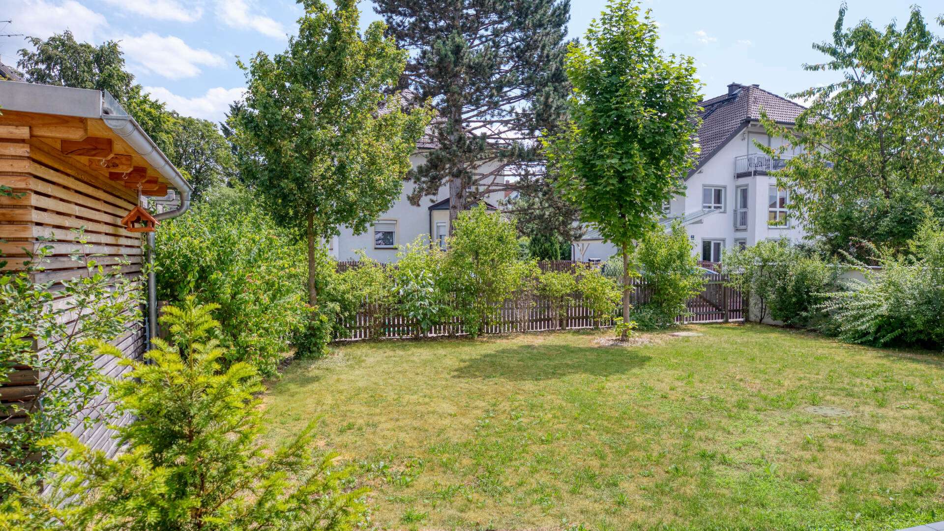 Communal garden of the garden apartment in Munich-Lerchenau with lawn area, trees, and garden shed
