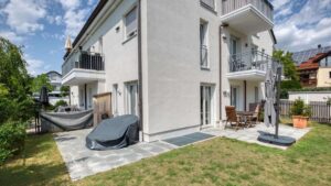 House view of the garden apartment in Munich-Lerchenau with a covered terrace, porch swing, and patio furniture
