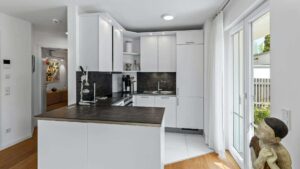 Open white kitchen in Lerchenau with a dark countertop and patio access.