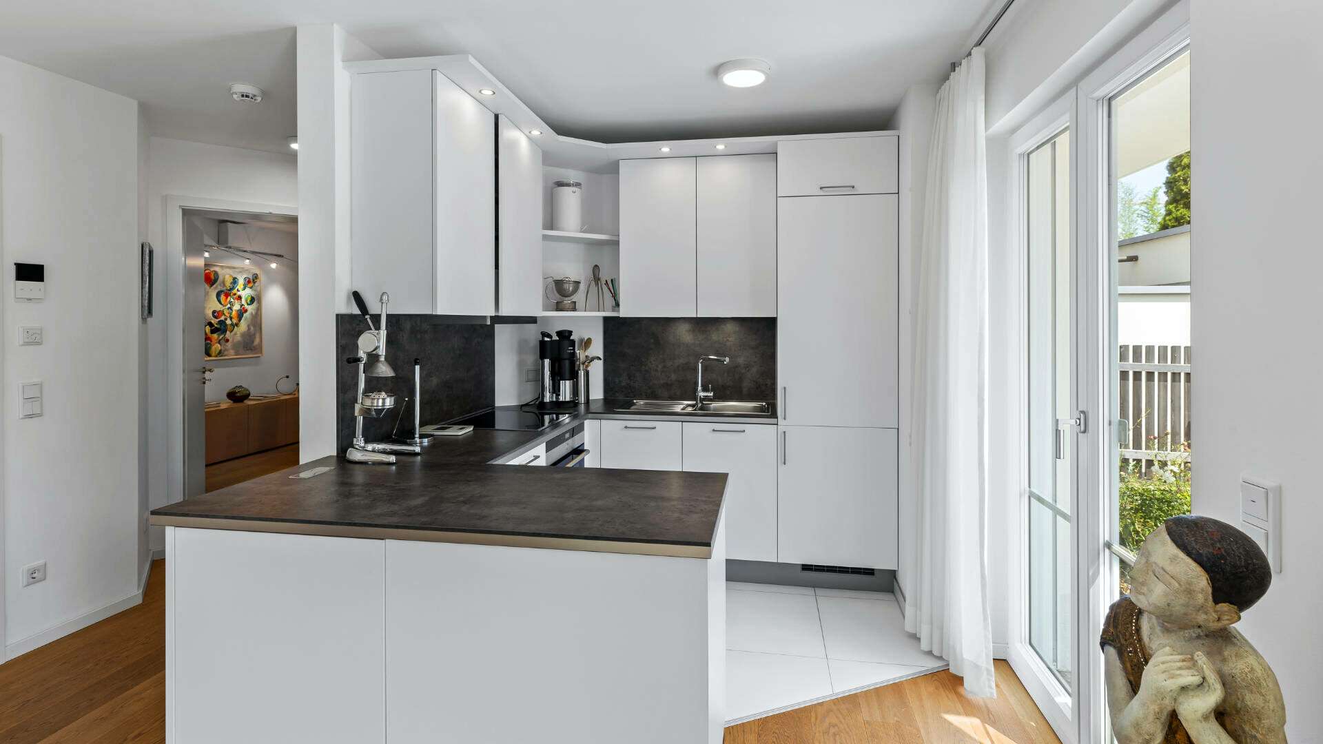 Open white kitchen in Lerchenau with a dark countertop and patio access.