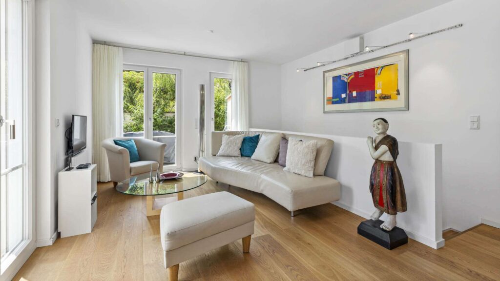 Living room in Lerchenau with a cream-colored sofa, art painting, and patio access.