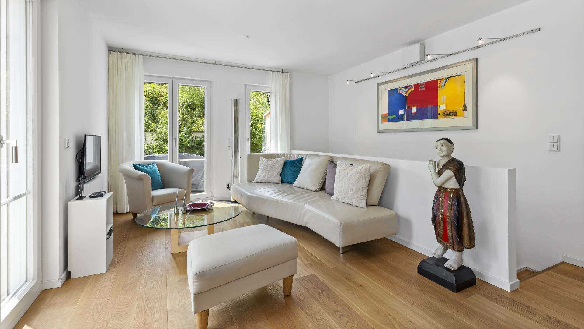 Living room in Lerchenau with a cream-colored sofa, art painting, and patio access.