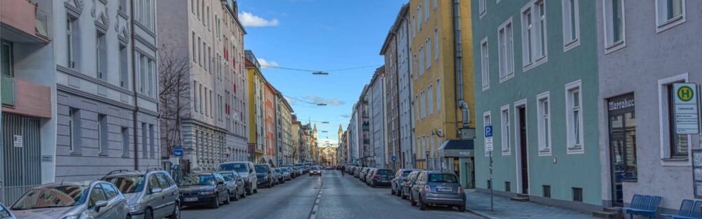 Altbaustraße in Maxvorstadt mit bunten Fassaden, parkenden Autos und Blick in Richtung Innenstadt.