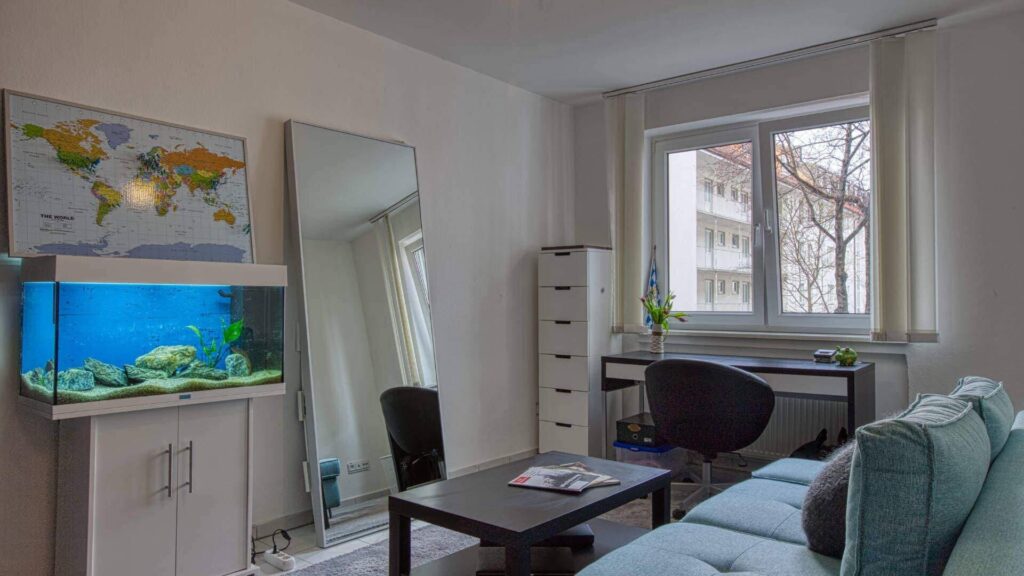 Möbliertes Zimmer mit Aquarium, Sofa und Schreibtisch in der Wohnung in München-Maxvorstadt