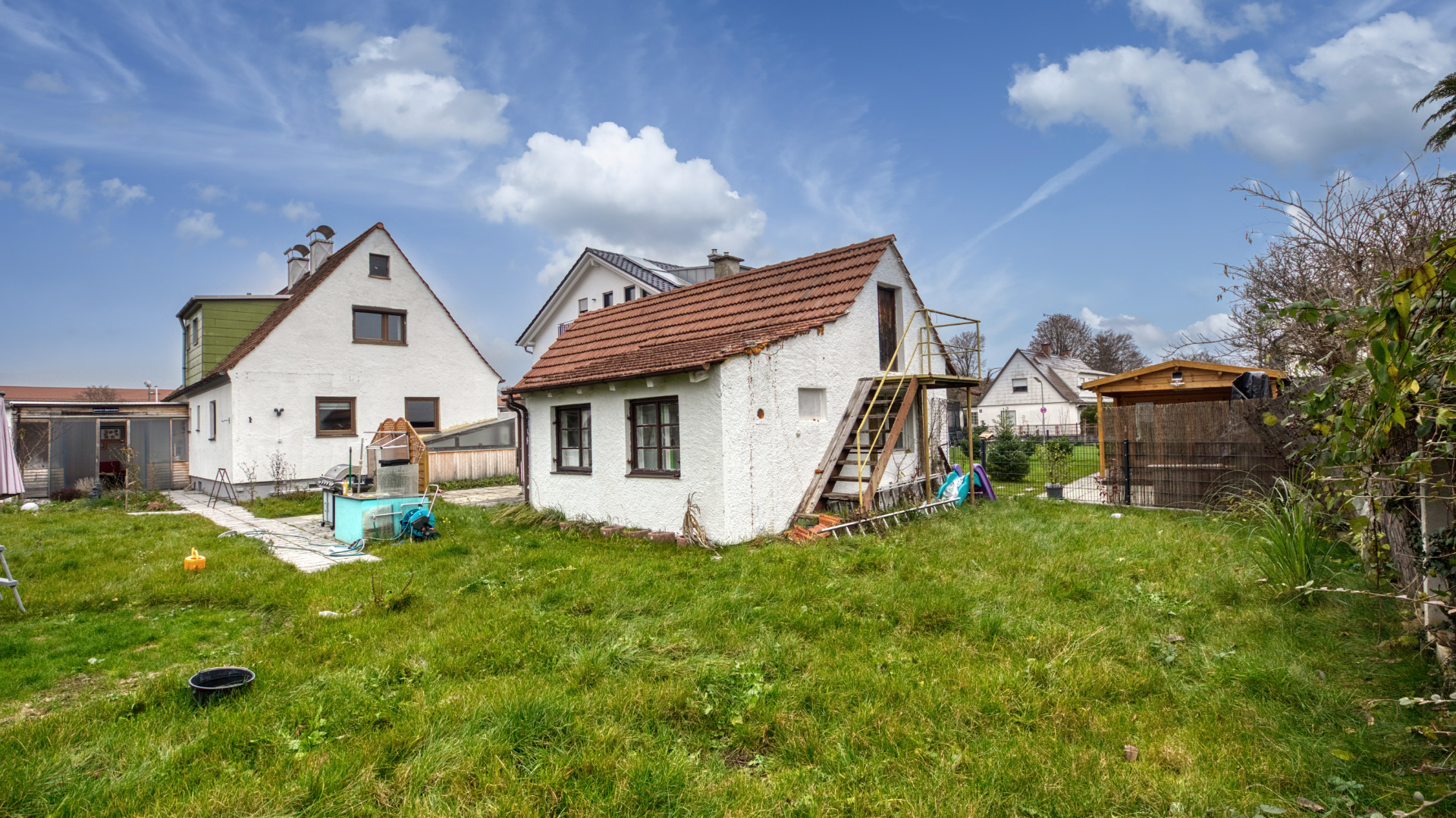 Garten mit Rasenfläche und kleinem Nebengebäude zwischen Wohnhäusern im Stadtteil Milbertshofen in München