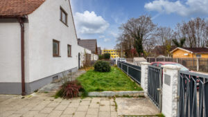 Gepflasterter Weg entlang der Hausfassade mit kleinem Rasenstück und Zaun im Stadtteil Milbertshofen in München