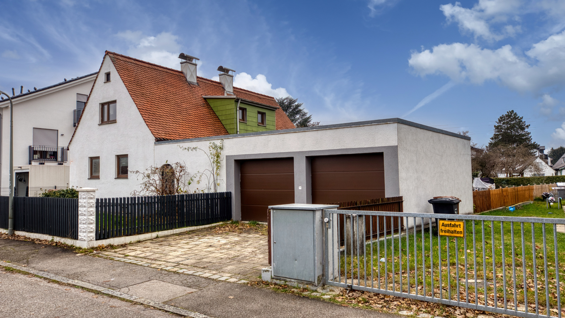 White house with a gable roof and dark double garage on a property in Milbertshofen.