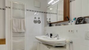 Bathroom in the apartment in Milbertshofen with sink, mirror, white towel radiator and tiled walls