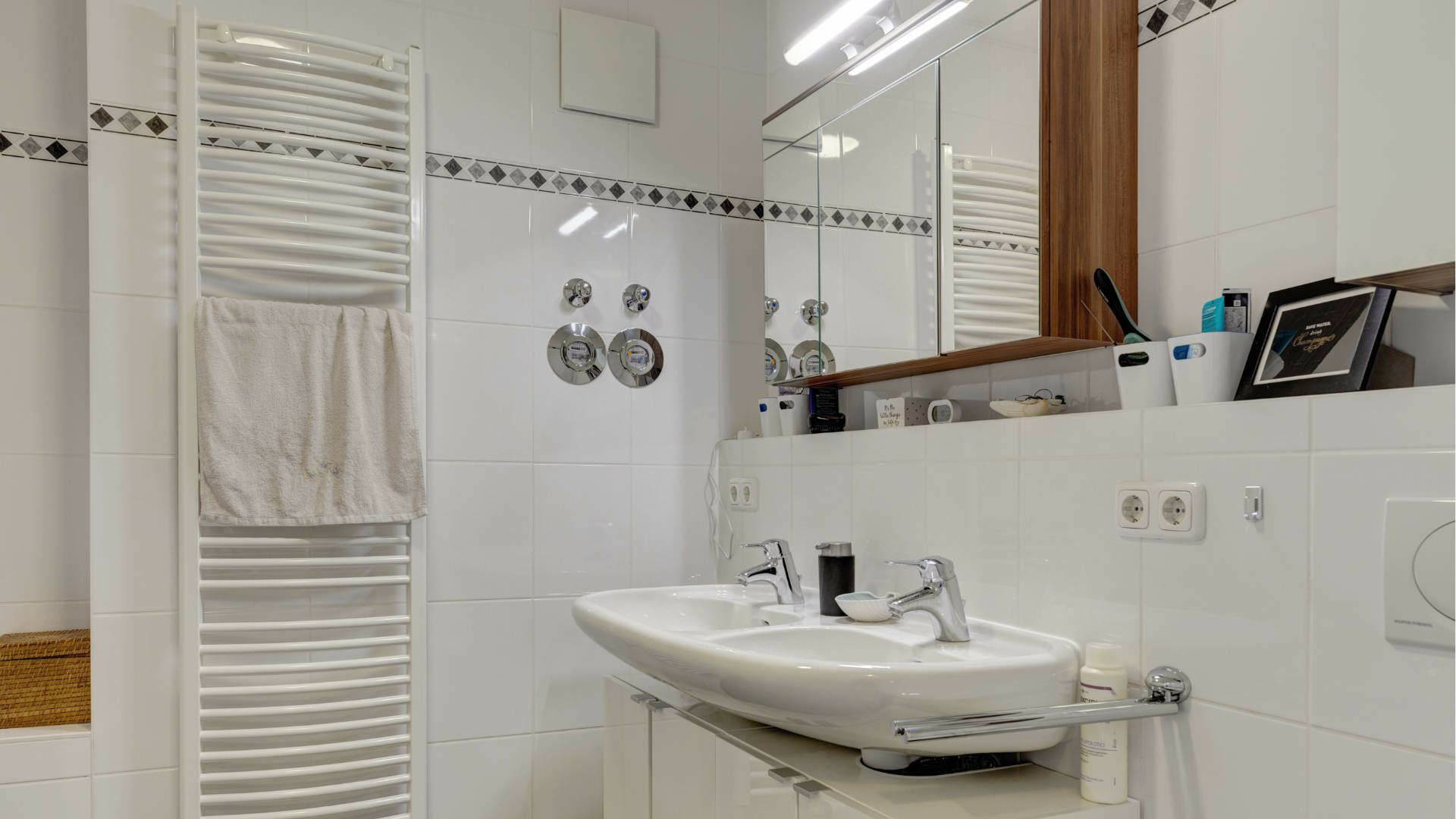 Bathroom in the apartment in Milbertshofen with sink, mirror, white towel radiator and tiled walls