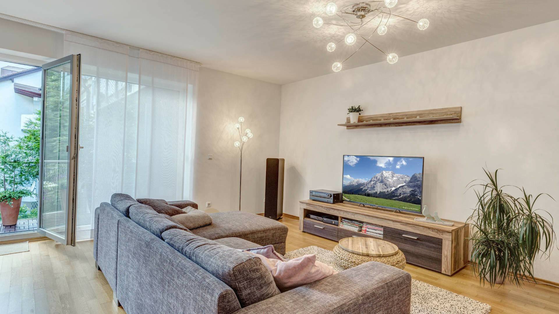 Living room with grey sofa and balcony access in an apartment in Munich-Milbertshofen
