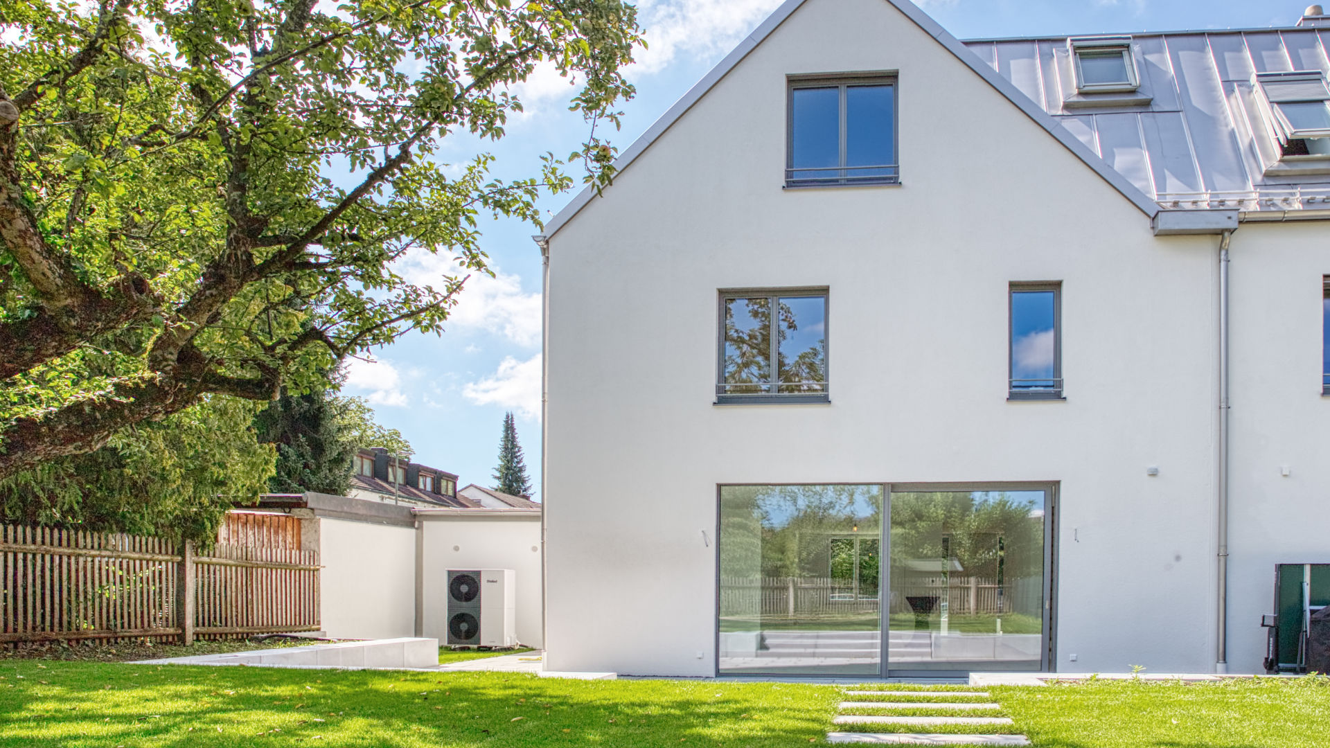 Modernes Einfamilienhaus mit weißer Fassade und großer Fensterfront zum Garten
