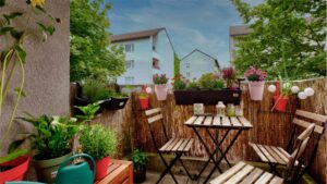 Begrünter Balkon mit Sitzgruppe und Blick auf Nachbarhäuser einer Wohnung in München-Moosach