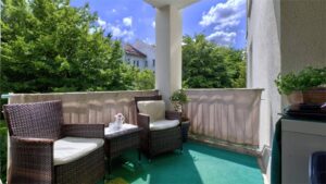 Überdachte Terrasse mit Rattanmöbeln und Grünblick einer Wohnung in München-Moosach