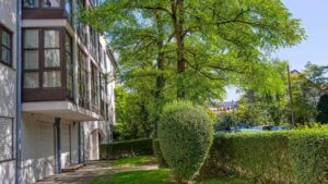 Facade of the residential complex with bay windows and trimmed hedge in the Munich district of Moosach