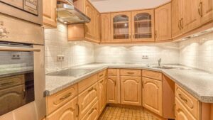 Built-in kitchen in Moosach with light wood decor, granite worktop and L-shaped kitchen island.