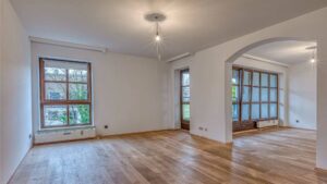 Empty living room with bay windows, round archway and parquet floor in Munich-Moosach