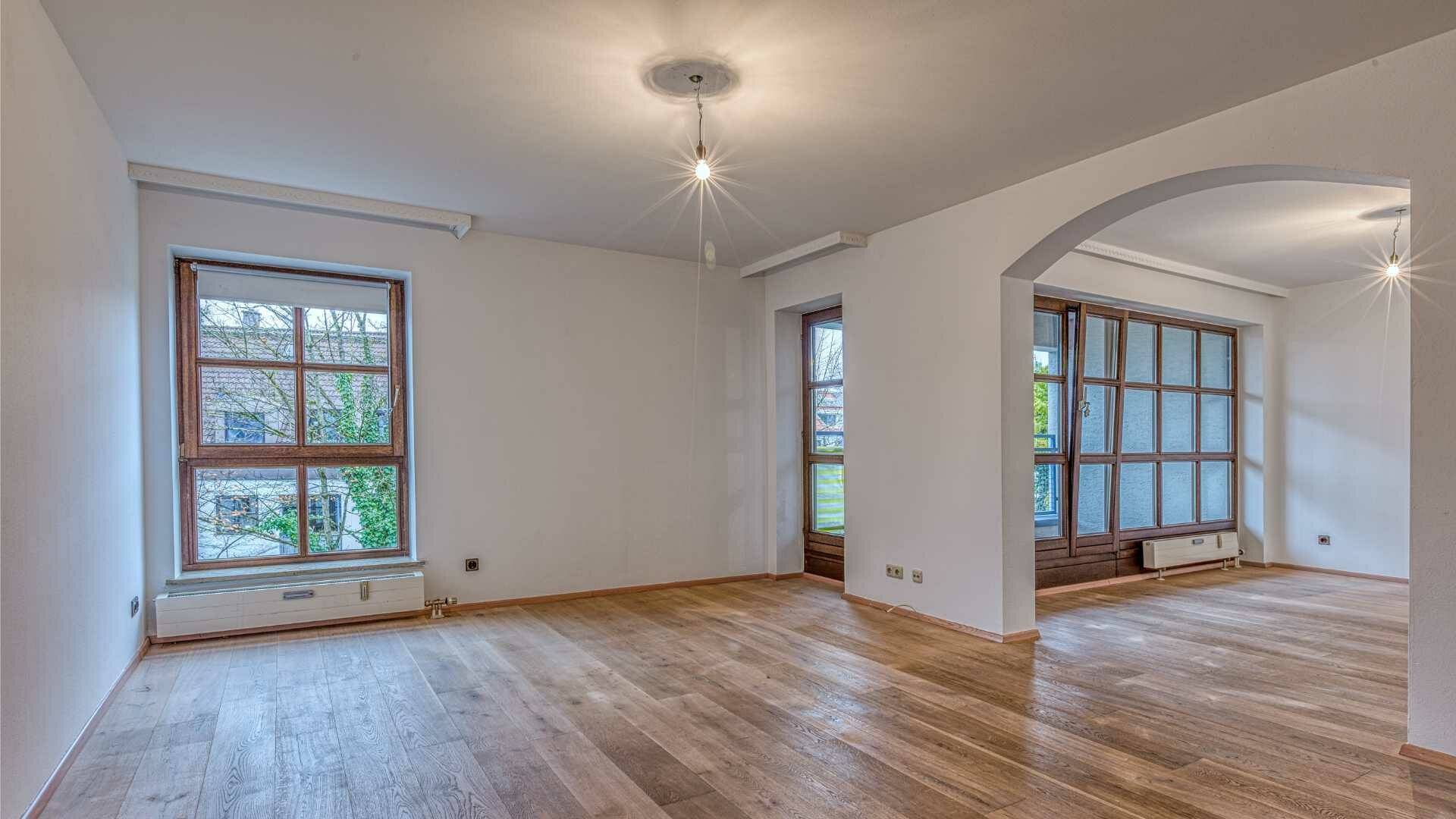 Empty living room with bay windows, round archway and parquet floor in Munich-Moosach