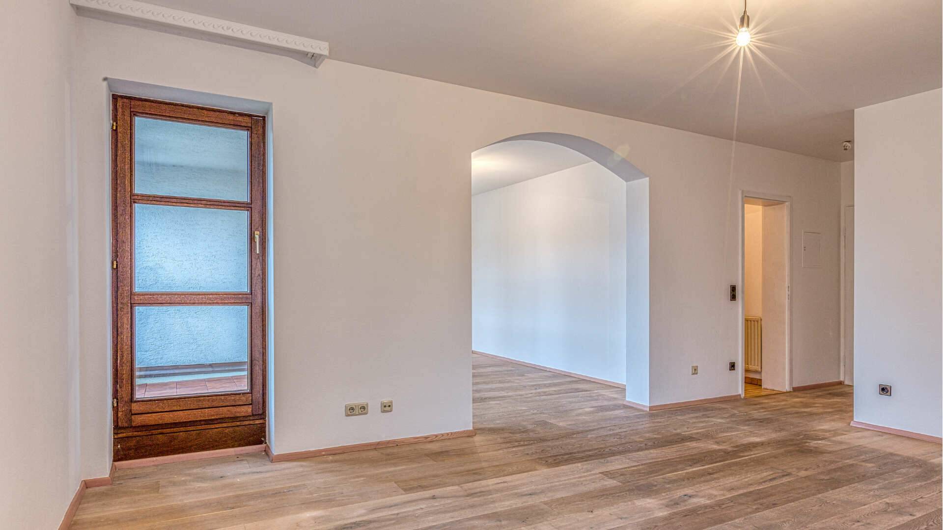 Empty room with round archway and light parquet floor in the apartment in Munich-Moosach