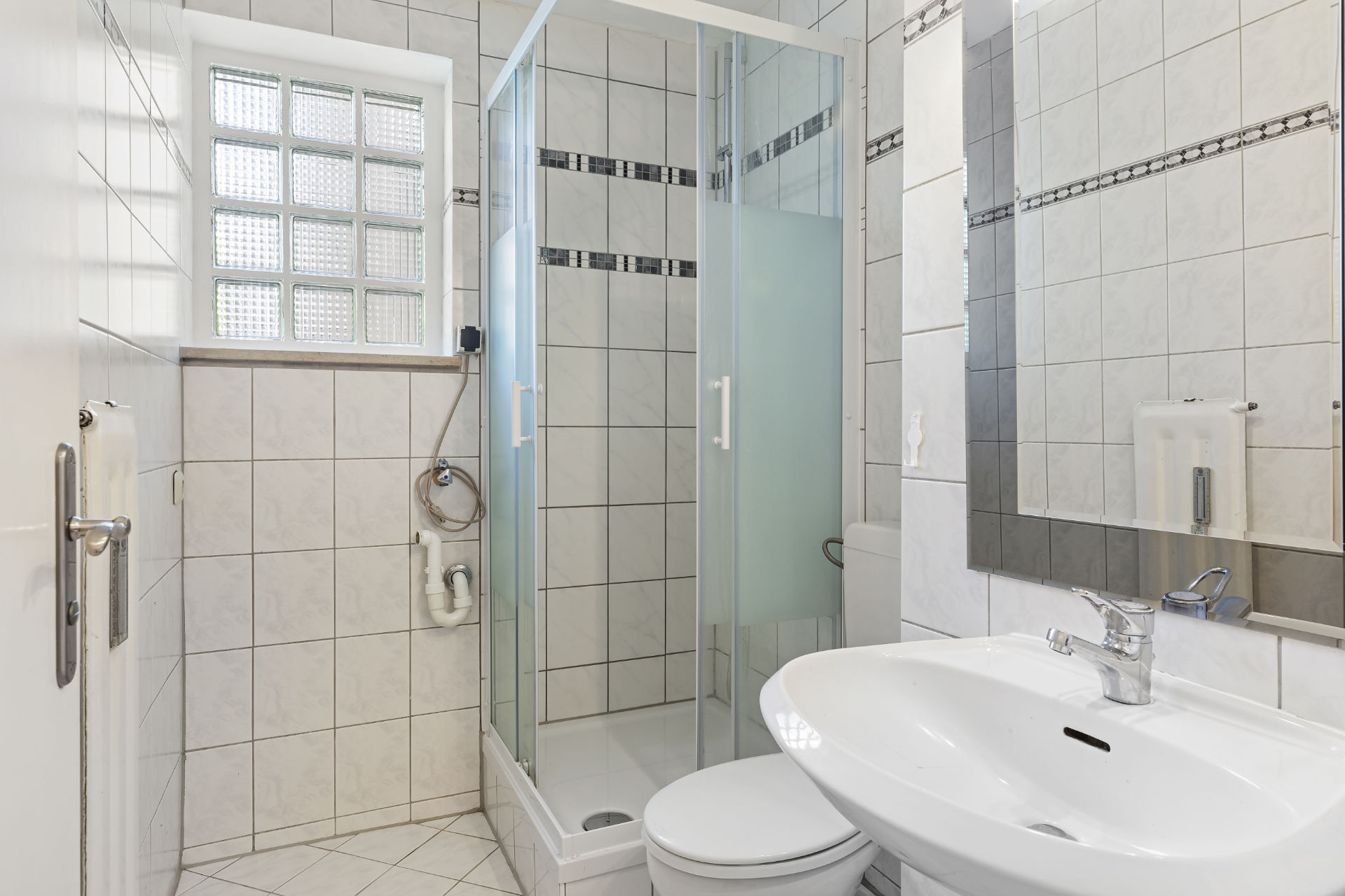 Simple bathroom in Fürstenried-West with shower, toilet, sink and tiles.
