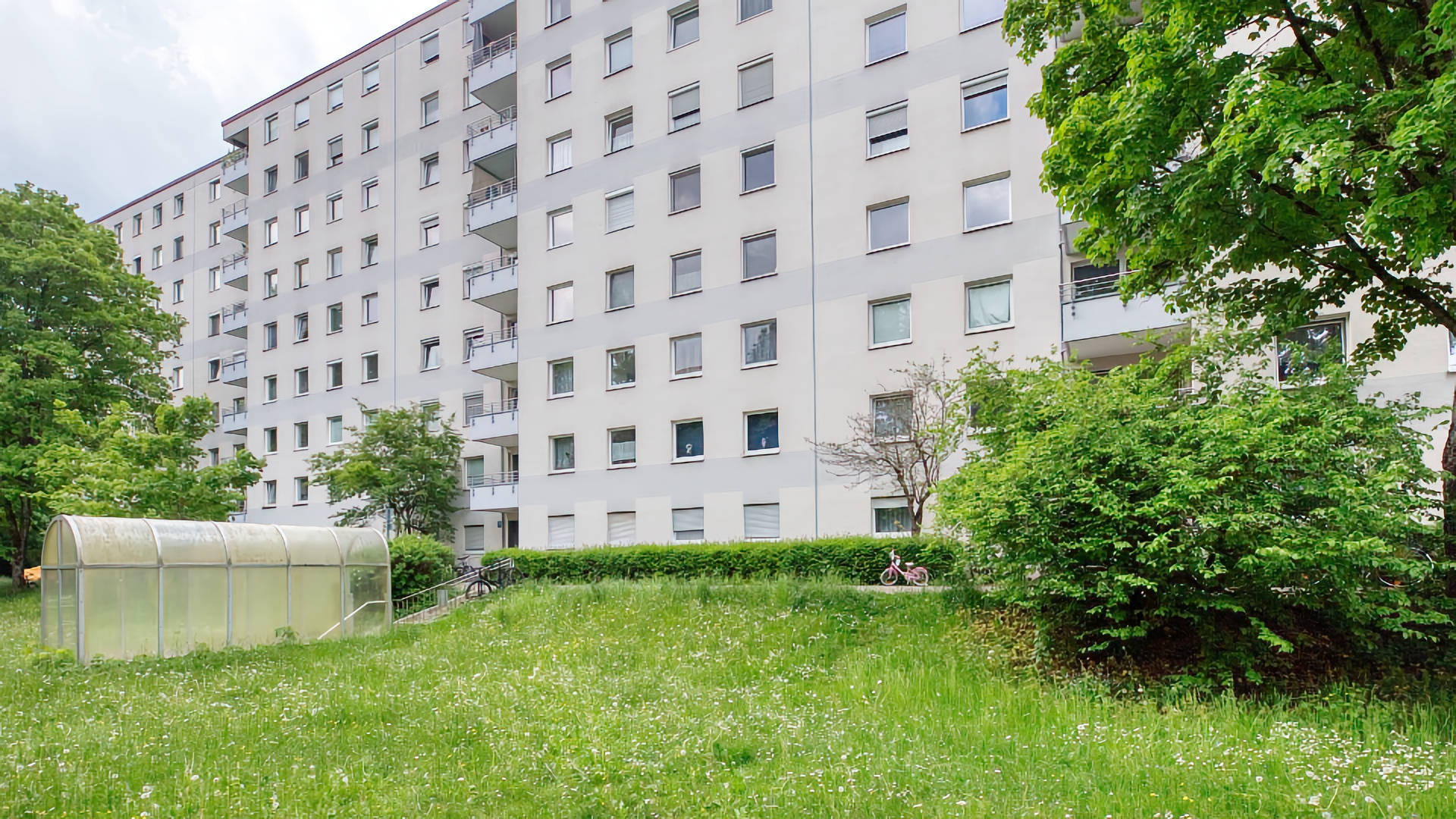 White high-rise building with many windows and a lawn in the Fürstenried-West district of Munich