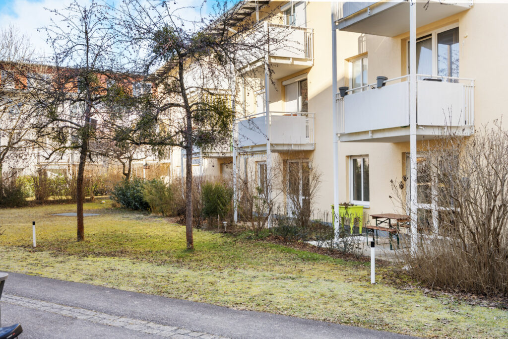 Facade of the Großhadern residential complex with balconies, bench, and garden between the buildings