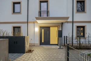 Entrance to the apartment building with a yellow front door and canopy in Munich-Pasing in the evening
