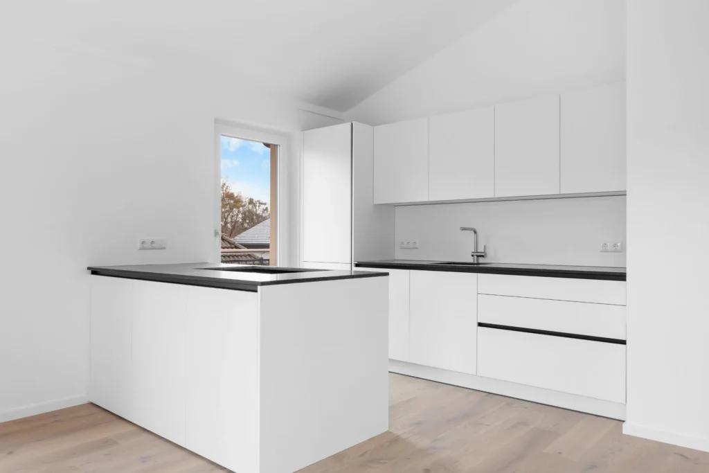 White fitted kitchen with kitchen island and roof window in a rental apartment in Munich-Pasing