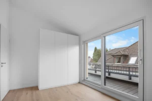 Empty bedroom with built-in wardrobe and access to the roof terrace in a rental apartment in Munich-Pasing