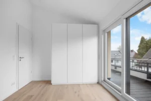 Bedroom of the Pasing rental apartment with white built-in wardrobe, slanted ceiling, and terrace access