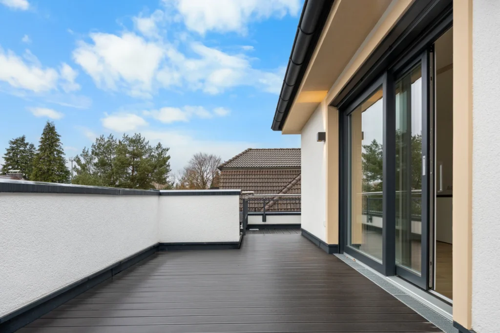 Rooftop terrace of the Pasing rental apartment with a view of a neighboring tiled roof and open terrace door