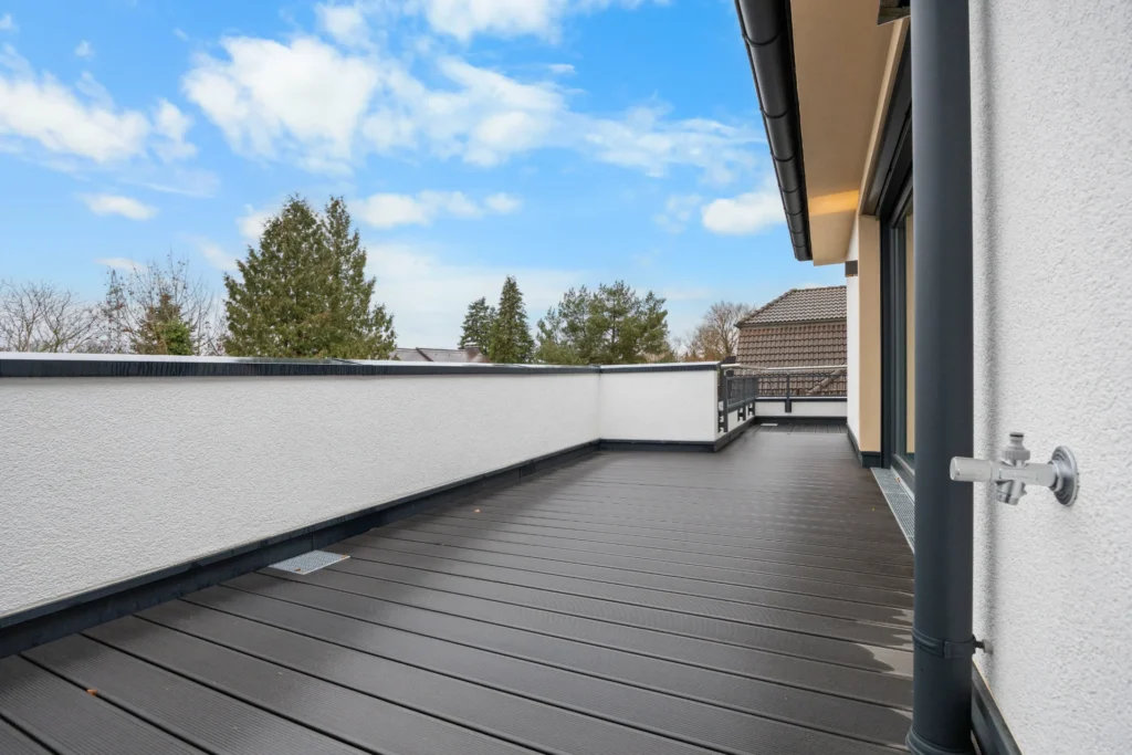 Spacious roof terrace of the rental apartment in Pasing with dark decking and a green view