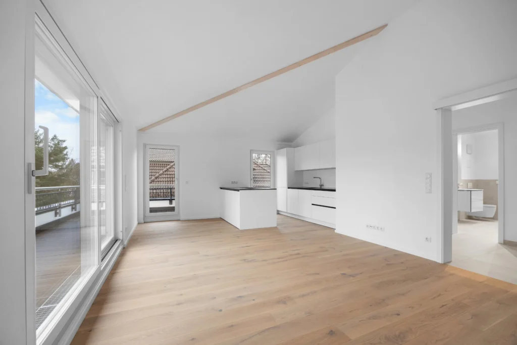 Open living area of the Pasing rental apartment with kitchenette, sloping ceiling, and view into the bathroom