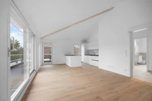Open living area of the Pasing rental apartment with kitchenette, sloping ceiling, and view into the bathroom