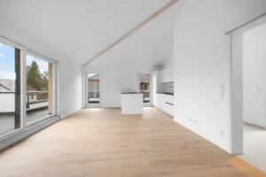 Living area of the Pasing rental apartment with sloping ceilings, freestanding kitchen unit, and passageway to other rooms