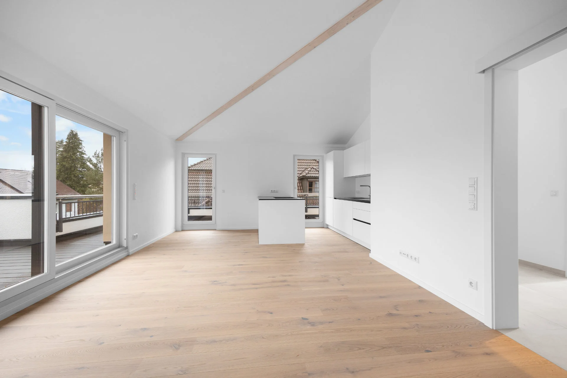 Living area of the Pasing rental apartment with sloping ceilings, freestanding kitchen unit, and passageway to other rooms