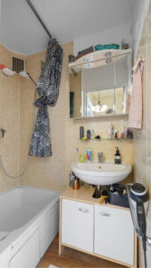 Compact bathroom with washbasin, mirrored cabinet, and bathtub in Schwabing apartment