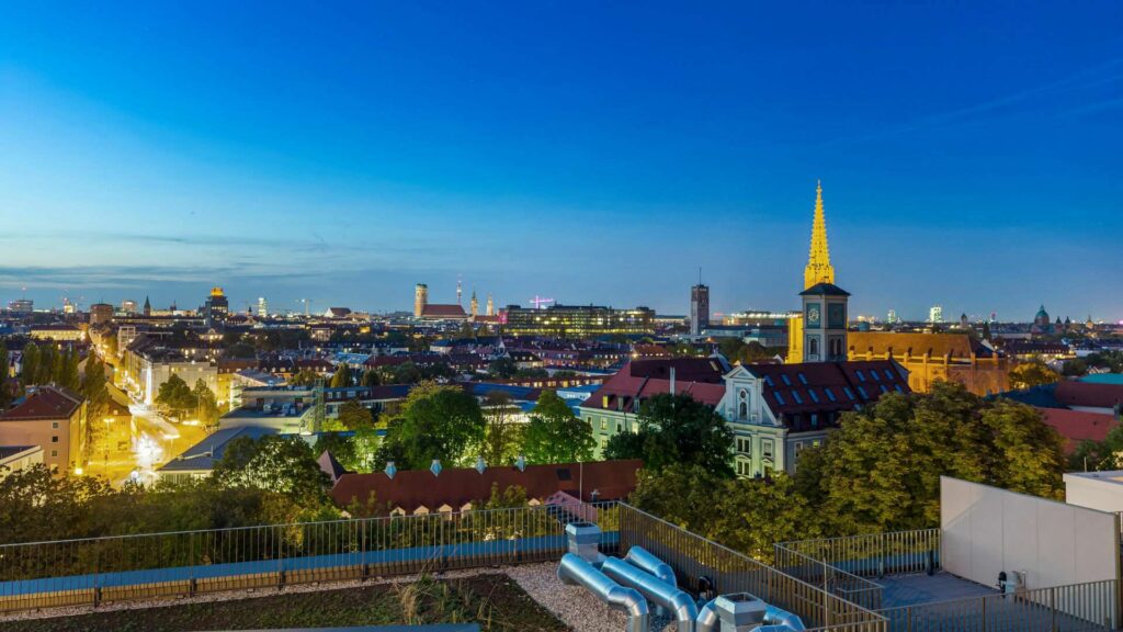Blaue Stunde über München mit beleuchtetem Kirchturm vom Nockherberg aus