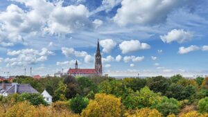 Blick auf einen Kirchturm hinter herbstlich gefärbten Bäumen vom Nockherberg aus