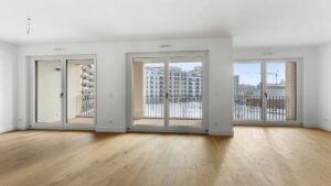Lichtdurchflutetes Wohnzimmer mit Fenstertüren und Blick auf moderne Nachbarbebauung am Nockherberg