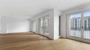 Weitläufiges, leeres Wohnzimmer mit mehreren Fenstertüren und Stadtblick am Nockherberg