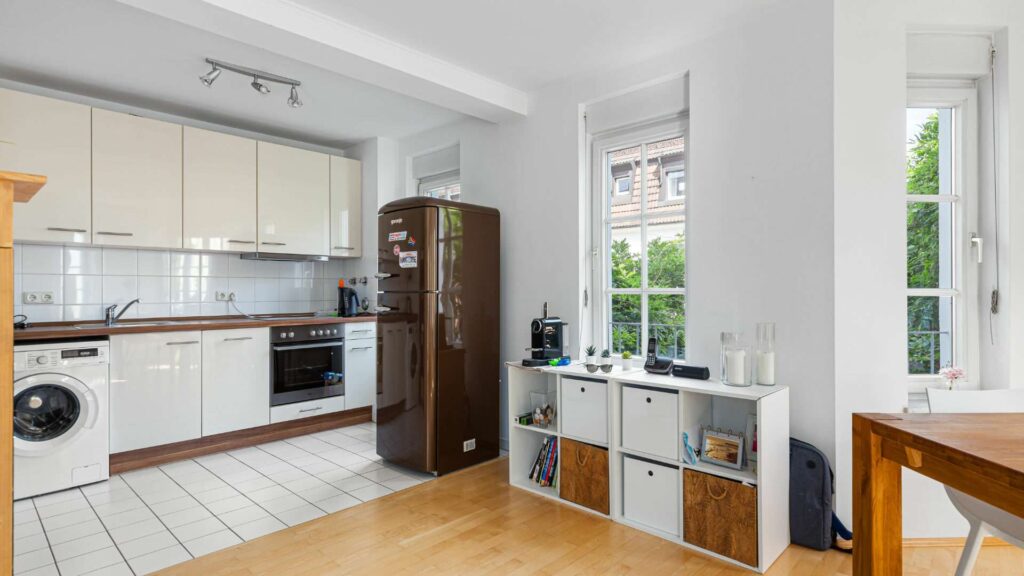 Kitchen of the apartment in Munich-Nymphenburg with cream-colored kitchen unit and windows