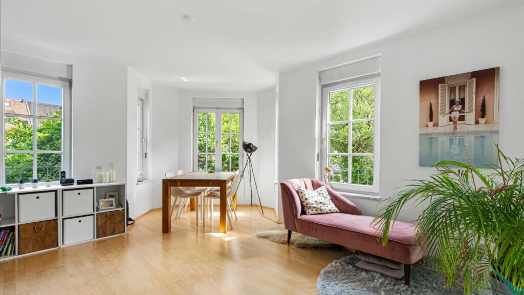Living room with seating area, bookshelf, and green plant in an apartment in Nymphenburg