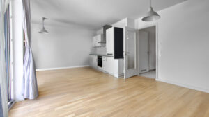 Unfurnished living space with open kitchenette and bright parquet flooring in an apartment in Munich-Obergiesing