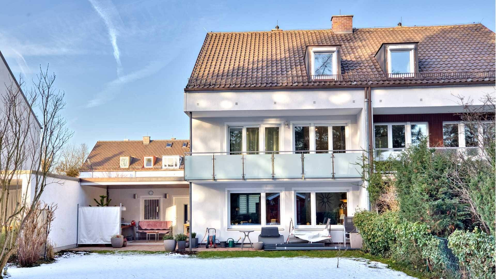 Weißes Doppelhaus mit Balkon und Terrasse im Schnee in München-Obermenzing.