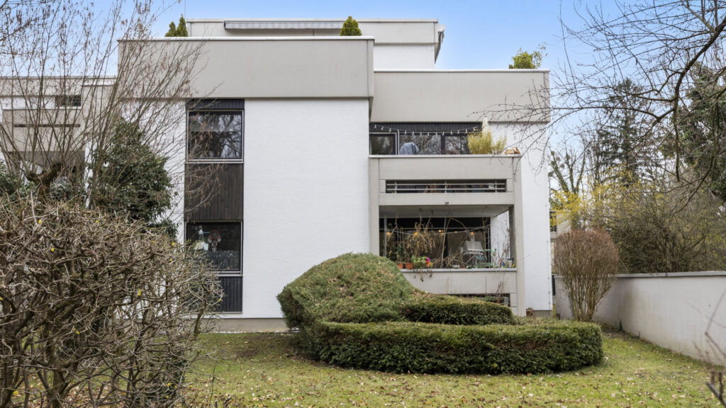 Modern building with large window areas and a curved form fence in the garden, Pasing