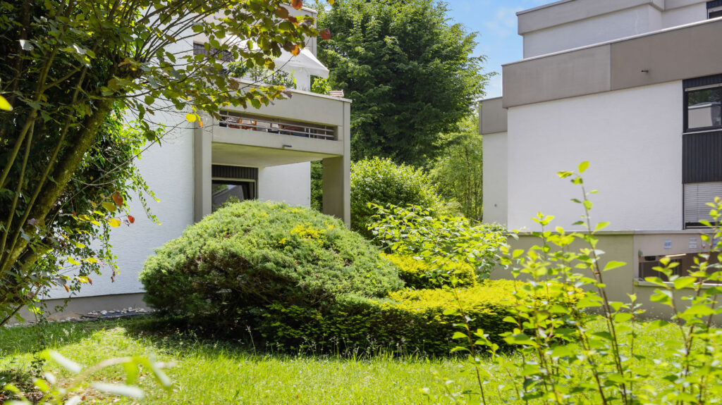 Entrance to the house with planted shrubs and a lawn in a residential complex in Munich-Pasing