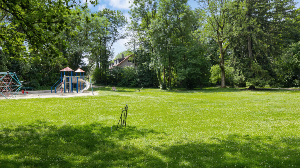 Green park area with playground and old tree canopy in the vicinity of the apartment Munich-Pasing