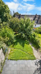 Top view of a green garden with lawn, trees, and patio paving in Planegg