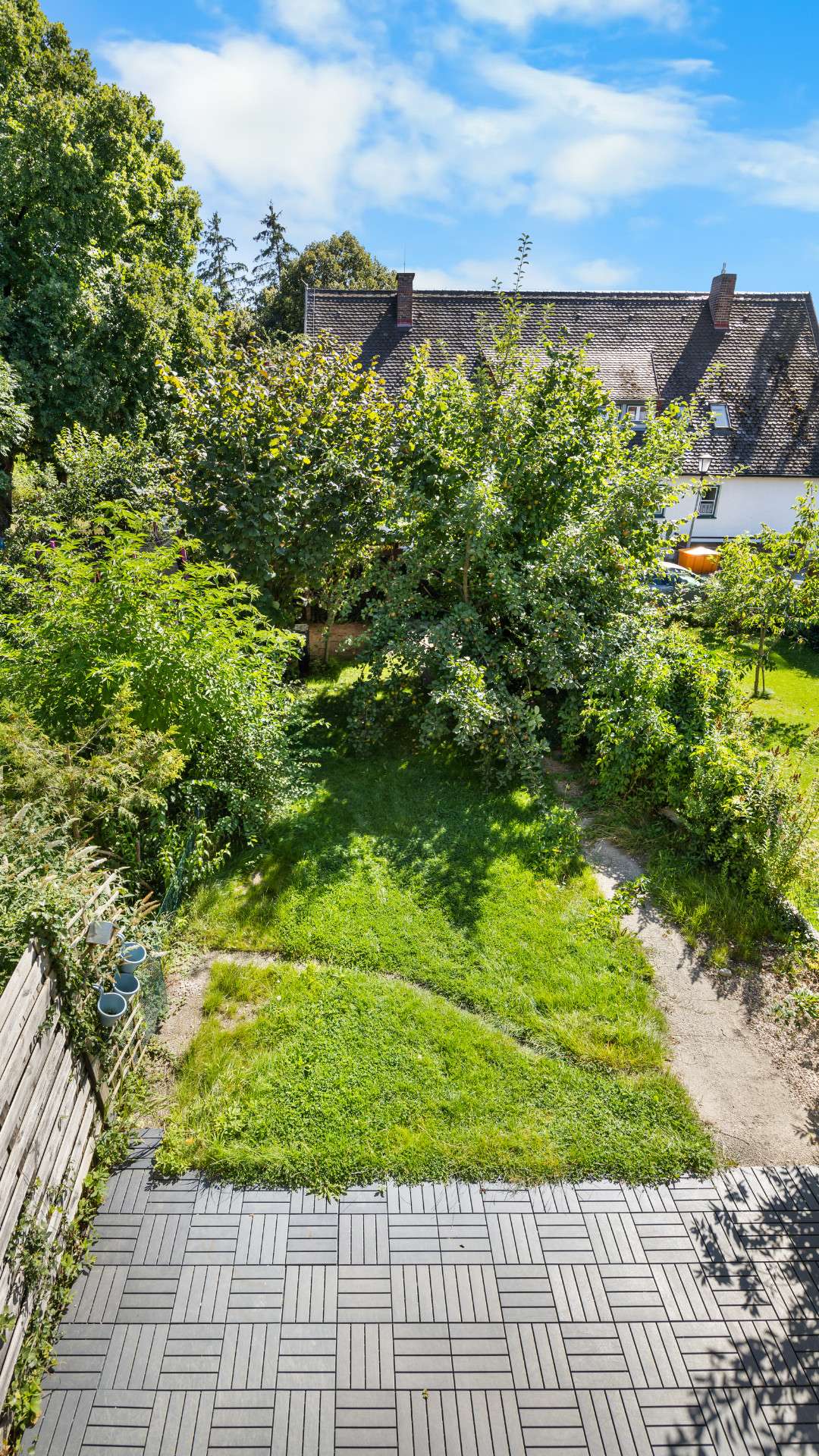Top view of a green garden with lawn, trees, and patio paving in Planegg